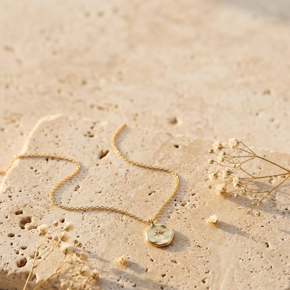 Gold coin necklace on travertine with dried flowers